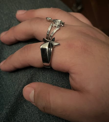 A reviewer's hand wearing the silver STAR RING on their index finger, with a second ring above it.