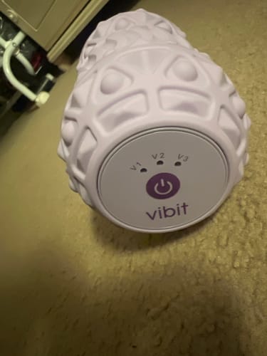 Customer's close-up of their purple Vibit ROLL massage roller, showing the power button and vibration level indicators.