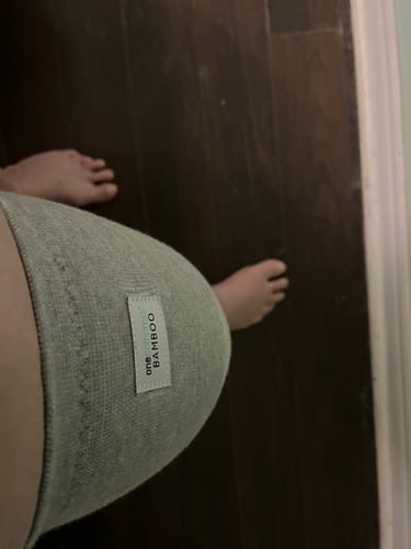 Customer's close-up, top-down view of a grey knee sleeve being worn on their leg.