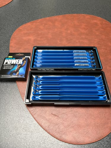 Recensent toont de XSH-B onderlijnen op blauwe houders in hun twee zwarte verpakkingen.