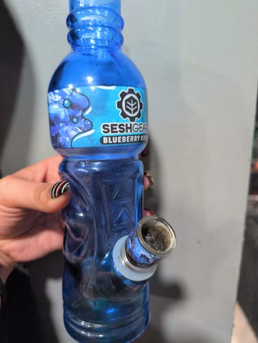 A reviewer holding the blue Terpade Beverage Bottle Glass Bong in their hand.