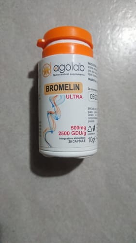 Un cliente mostra il flacone di integratori Bromelin ULTRA su una superficie piana.