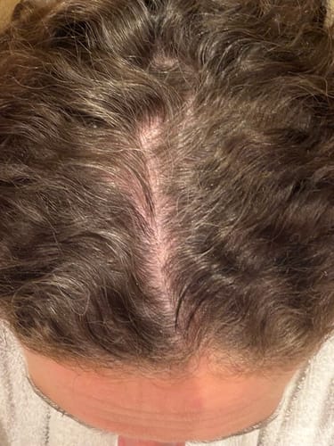 Close-up of a reviewer's parted hair showing grey roots before using the Instant Dye Shampoo.