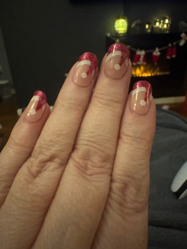 Customer's hand showing nails with a festive red glitter Santa hat design using Snowberry gels.