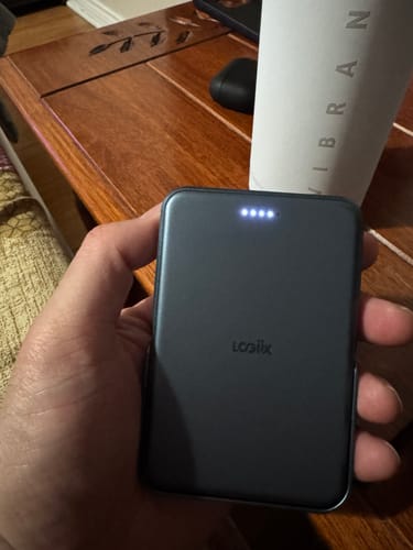 Customer holding the dark grey Piston Power 5000 Stance Mag power bank, showing the four white battery indicator lights.