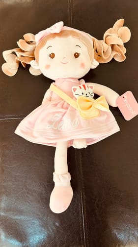 Customer's Personalized Milly Girl doll with the name 'Lena' embroidered on its pink dress and a pet cat in its bag.