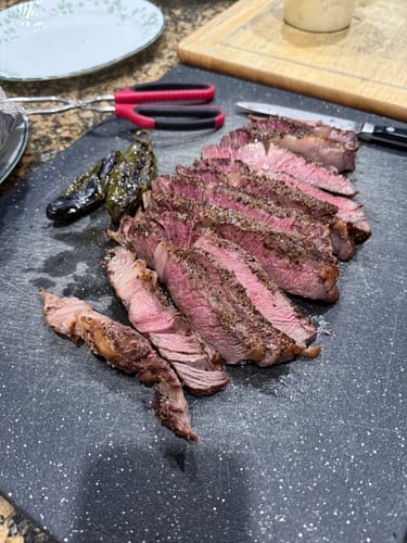 Customer's cooked Tomahawk Prime Rib Roast, sliced thick on a dark cutting board to show the pink interior.
