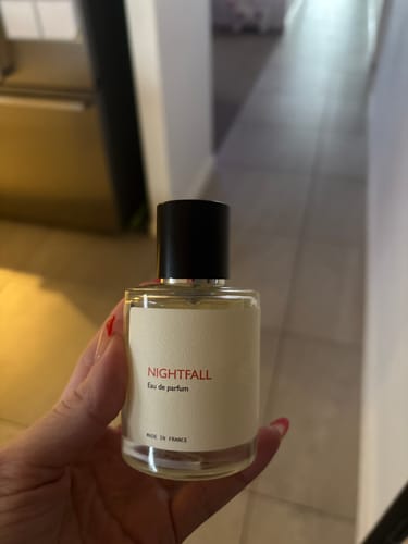 Customer's hand holding a clear glass bottle of Nightfall Eau de parfum.