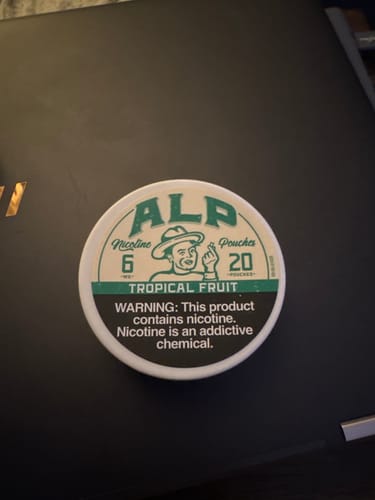 Customer's can of ALP Tropical Fruit Nicotine Pouches resting on a dark surface.