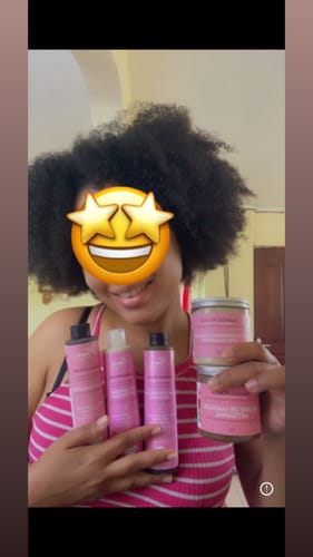 Une cliente souriante aux cheveux crépus tenant les produits du pack routine Mango POUSS.