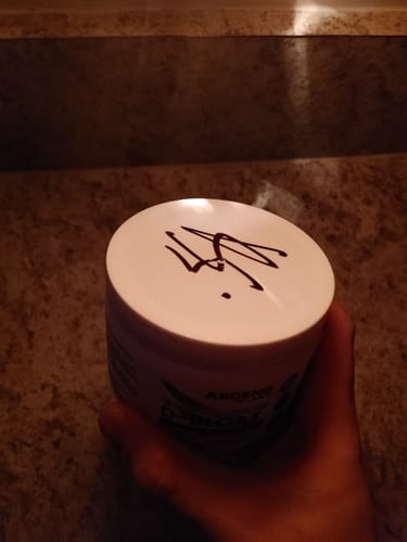 Reviewer's hand holding a white tub of D-BLOAT, showing the lid which has been signed.