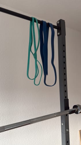 Reviewer's blue and green Premium Latex Resistance Bands hanging from a pull-up bar.