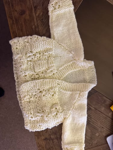 Customer's completed baby matinee jacket from the Lemonade Days knitting kit, shown in a pale yellow yarn with a lacy pattern.