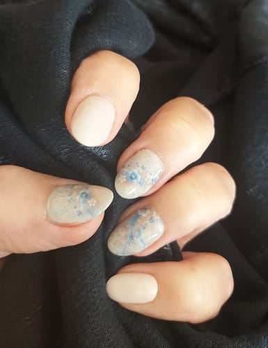 Kundin zeigt ihre Maniküre mit blumigen Bands Of Blooms Nagel-Folien und cremefarbenen Akzentnägeln.