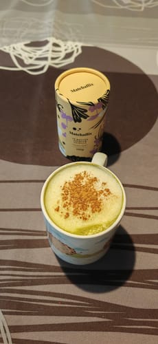 Un cliente muestra su taza de Té Matcha Vainilla Premium espumoso junto al empaque del producto.