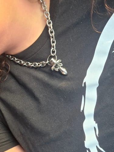 Close-up of a customer wearing the silver SPIDER PACIFIER CHAIN necklace against a dark shirt.