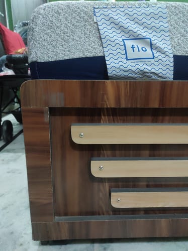 Close-up of a customer's Flo Anti-Gravity™ Latex Mattress corner with the logo tag on a wooden bed frame.