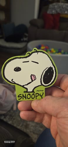 Customer holding the green Peanuts Snoopy Notepad, showing the cover with Snoopy's happy expression and tongue out.