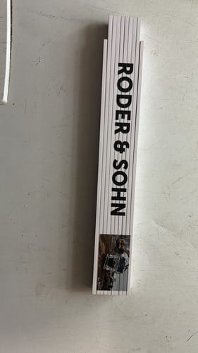 Kunde zeigt den zusammengeklappten Zollstock, personalisiert mit schwarzem Text und einem Foto.