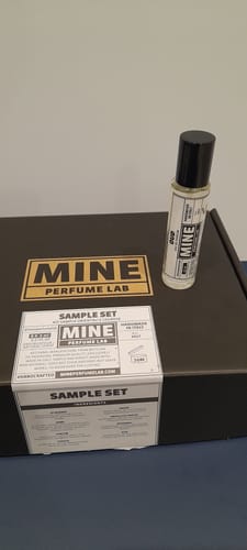 Recensore mostra il profumo OUD in formato campione sulla sua confezione nera.