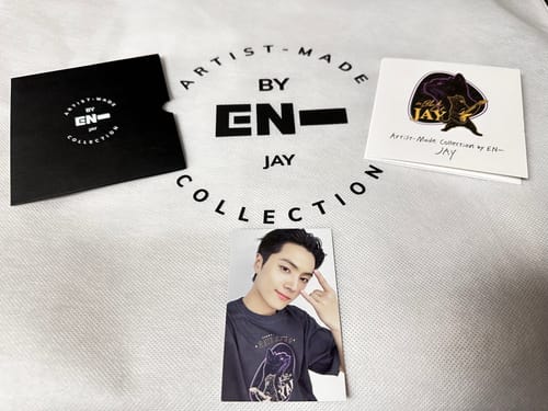 Reviewer's photocard and packaging for the ENHYPEN JAY'S T-SHIRT laid out on the collection's dust bag.