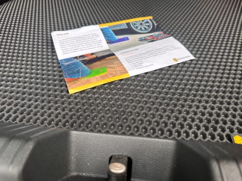 Zbliżenie na czarną matę do bagażnika recenzenta, ukazujące jej charakterystyczny wzór plastra miodu.