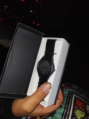Customer holding the open black box containing the Premium Engraved Wood Watch with a black leather band.