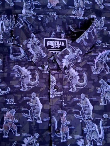 Close-up of a customer's Godzilla 'Gojivolution' shirt showing the dark, detailed pattern of various Godzilla eras and the collar.