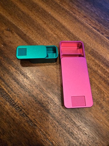 Reviewer's green nano pill case and pink mission pill case on a wooden surface.