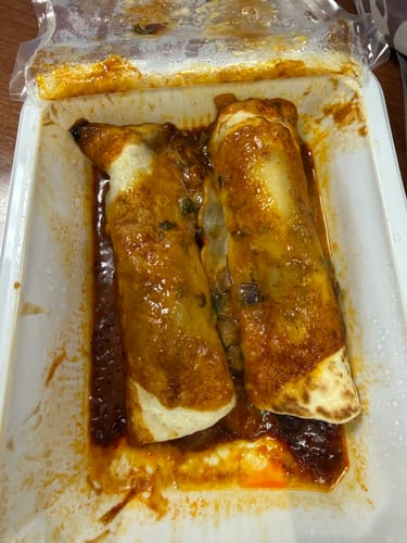 Customer's Chicken Enchiladas in the meal tray, covered with red sauce and melted cheese.