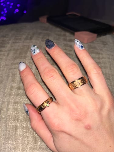 Customer's hand wearing two gold-colored rings from the jewelry bundle, one featuring a celestial design.