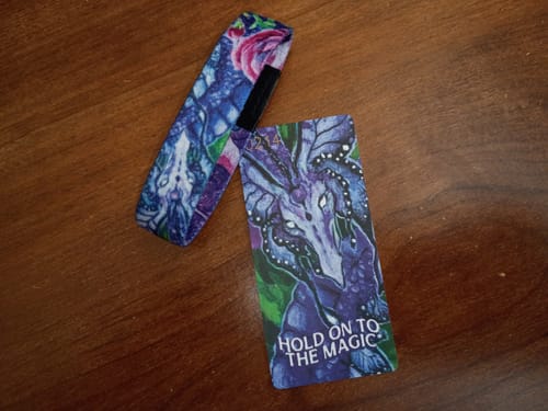Reviewer's colorful 'Hold On To The Magic' bracelet and its matching card displayed on a wooden surface.