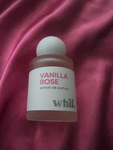 Customer's bottle of Vanilla Rose extrait de parfum resting on a shiny pink fabric.