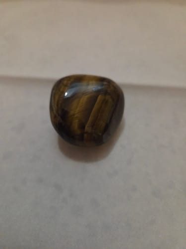 Client présentant sa très belle pierre Oeil de tigre polie sur une surface unie.