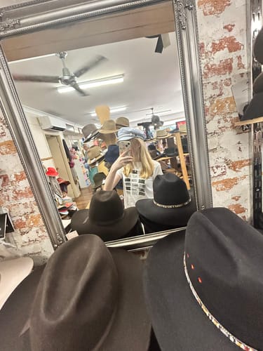 Reviewer taking a mirror selfie wearing the graphic one-way ticket baby tee in a shop.