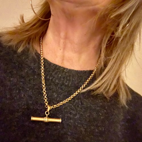 Customer wearing the shiny XL T-Bar Necklace over a dark grey sweater, showing its size and chain.