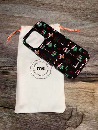 Customer's Grinchmas black phone case with a repeating holiday pattern, resting on its white drawstring pouch.