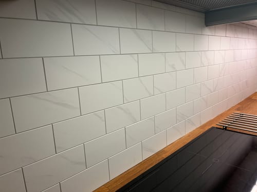 Kundens hvite Stein subway marmor veggfliser installert på en kjøkkenvegg over en benkeplate.