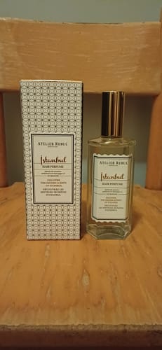 Recensent toont de fles Istanbul Haarparfum en de doos op een houten stoel.