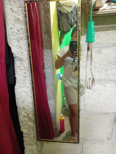 Un cliente se refleja en el espejo con marco tipo mármol y dorado, apoyado en una pared.