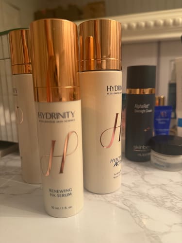 Customer's collection of Hydrinity Renewing HA Serum bottles on a marble bathroom counter.