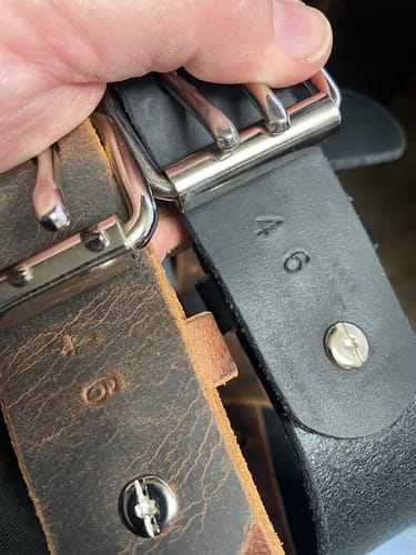 Customer holding the brown Woodstock belt next to a black belt, showing both are stamped with size 46.