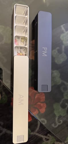 Customer's Weekly AM-PM Pill Case 2.0 with the silver AM and grey PM sections separated. The AM case is open showing pills inside.