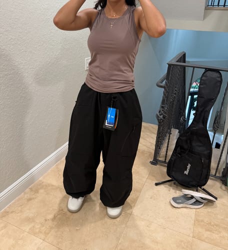 Customer trying on the baggy black snow pants indoors, showing the fit from the front.