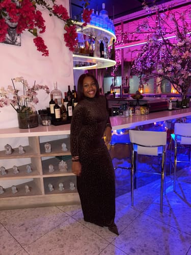 Reviewer smiling while wearing the Burnout Print Turtleneck Maxi Dress in a stylish bar.