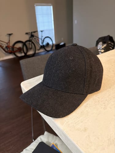 Customer's dark gray Big Structured Baseball Felt Cap sitting on a white countertop in a home setting.