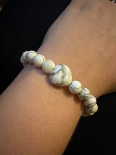 Customer wearing a white and grey beaded bracelet with a heart-shaped stone on their wrist.