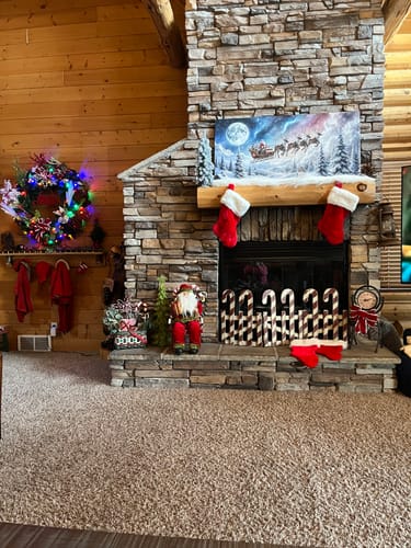 Customer's Christmas print of Santa's sleigh ride displayed above a decorated stone fireplace.