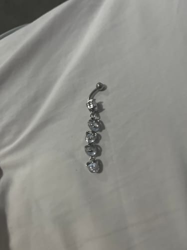 Reviewer's Collapsing Hearts Belly Bar with a dangling charm of heart-shaped gems on a white surface.