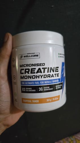 A customer holds a white jar of Wellcore Micronised Creatine Monohydrate in the Tropical Tango flavor.